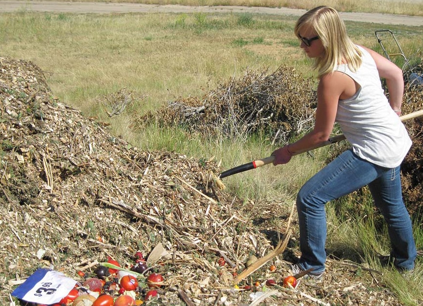 woman turning a pile of compost